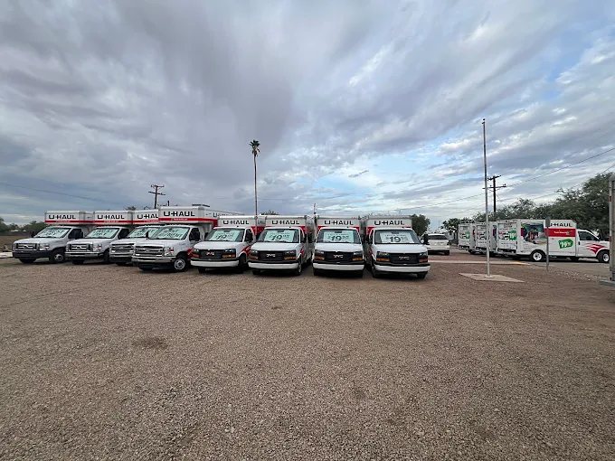 Trucks lined up across a wide gravel lot under clouds