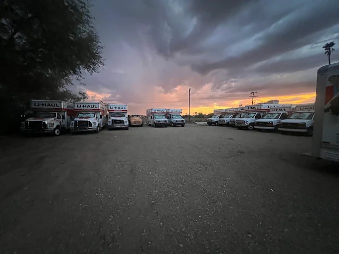 Wide gravel lot at sunset with U-Haul trucks parked along the edges