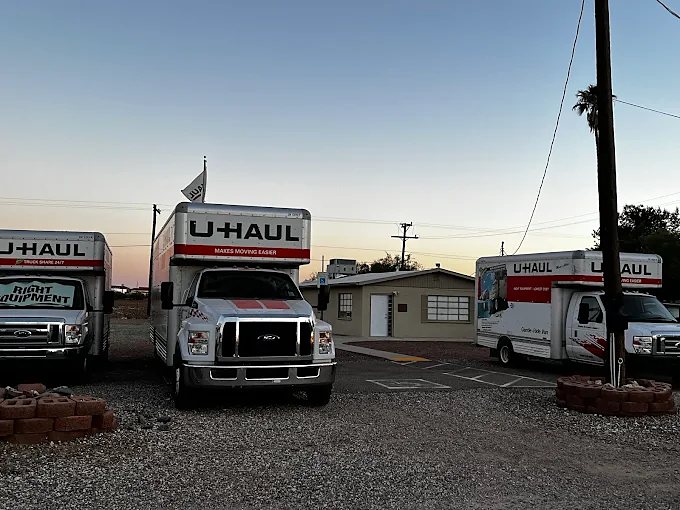 The MaranaRVParking office at dusk with U-Haul trucks out front
