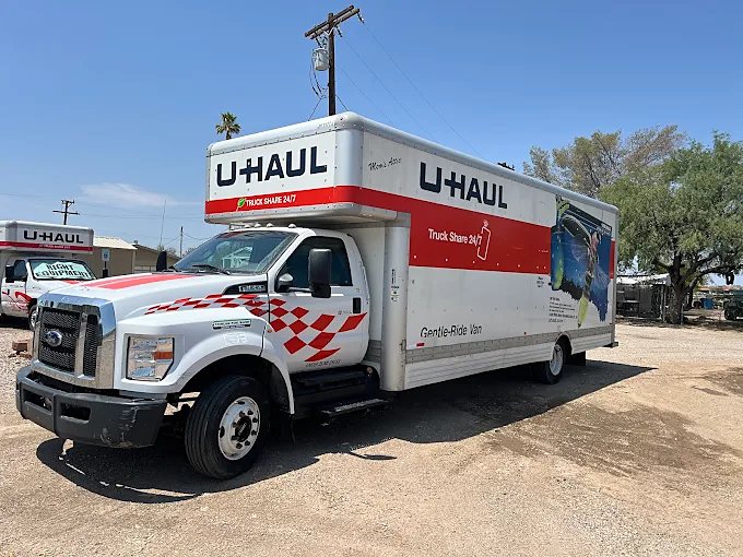 A U-Haul box truck parked on the gravel lot